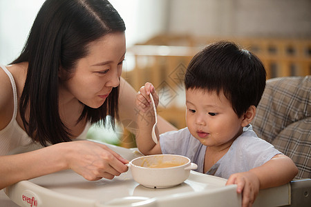 孩子趴在粥碗上享乐25岁到29岁好奇妈妈喂宝宝吃饭背景