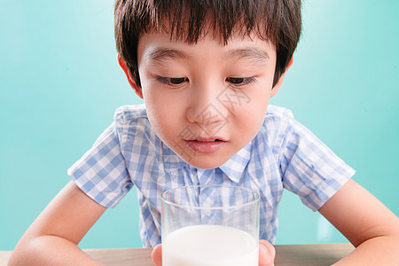 儿童无忧无虑微笑小男孩看着一杯牛奶背景图片