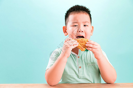 东方人影棚拍摄成长可爱的小男孩吃炸鸡图片