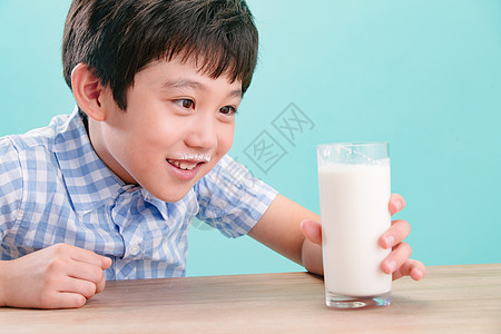 无忧无虑亚洲幸福小男孩看着一杯牛奶图片