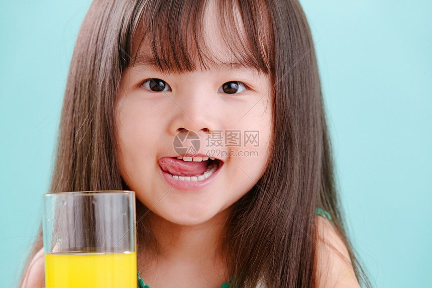 注视镜头影棚拍摄微笑可爱的小女孩喝饮料图片