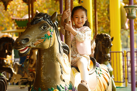 游乐园一个小女孩在玩旋转木马图片