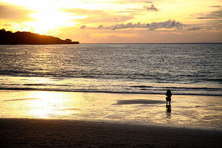 海浪风景晚霞巴厘岛海滩上的游客剪影图片