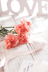 桌上的康乃馨花和信封贺卡图片