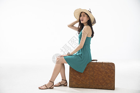 坐着旅行者自信青年女人坐在行李箱上图片