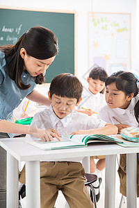 男孩和女孩学习奉献现代老师和小学生们在教室里背景