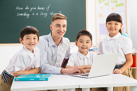 电脑学生电脑未成年学生成年人教师和小学生在教室里背景