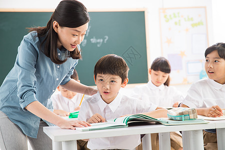 摄影相伴小学女生老师和小学生们在教室里高清图片