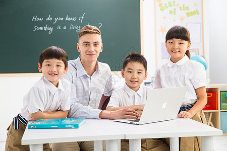 电脑学生相伴电脑户内教师和小学生在教室里背景