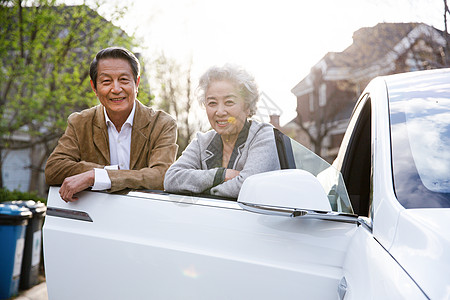 老年社区老年夫妇站在汽车旁背景