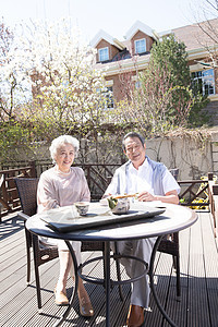 垂直构图高雅70多岁老年夫妇在庭院喝茶图片