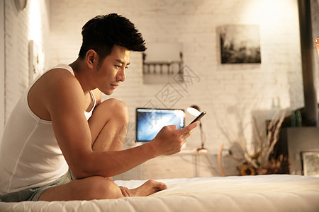 休闲追求起居室简单青年男人在卧室玩手机图片