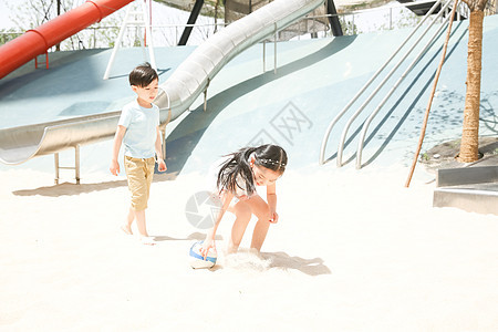 休闲装高兴可爱的儿童在沙子里踢球图片
