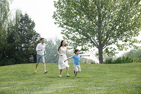 白昼三个人郊游一家三口在草地上奔跑图片