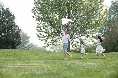 幸福一家东方人人健康生活方式一家三口在草地上放风筝背景
