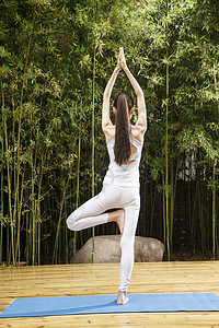 单腿站立青年人高举手臂单腿站着青年女人练习瑜伽背景