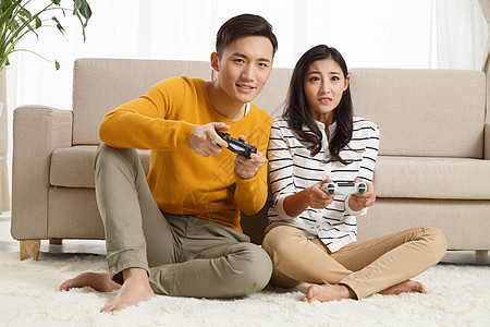 25岁到29岁亚洲人青年情侣坐着沙发上玩游戏图片