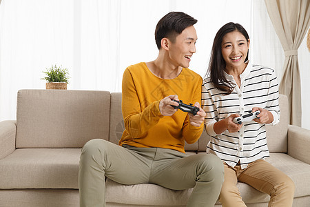 水平构图亚洲享乐青年情侣坐着沙发上玩游戏图片