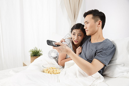 和谐家庭生活亚洲人青年情侣坐着床上看电视背景图片