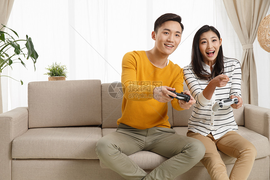 女朋友青年伴侣遥控器青年情侣坐着沙发上玩游戏图片