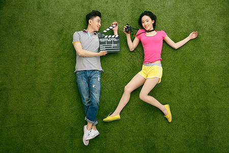 年轻女人正上方视角休闲青年情侣躺在草地上玩耍图片