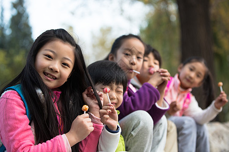 棒棒糖树幸福东方人可爱的男孩女孩在户外玩耍背景