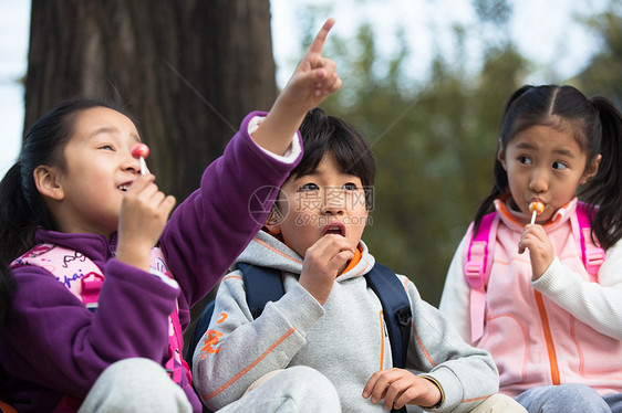 坐着乐趣伙伴可爱的男孩女孩在户外玩耍图片