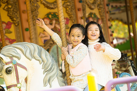 中国儿童仅儿童天真秋游两个小女孩在玩旋转木马背景