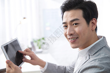 东亚办公区轻松办公青年商务男人拿着平板电脑办公背景图片