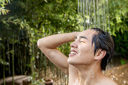 亚洲享受露齿一笑年轻男人在户外淋浴洗头图片