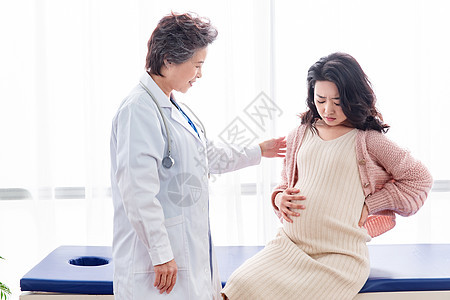 亚洲人可靠床医生给孕妇检查身体背景图片