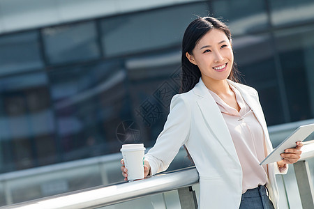 拿着平板电站在户外的商务女士图片