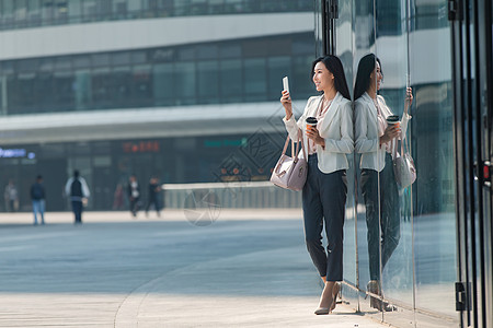 互联网大楼青年商务女人站在户外看手机背景