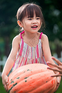 户外健康的高兴东方儿童抱南瓜图片