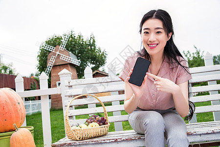 美丽的水平构图享乐青年女人坐在户外展示手机图片