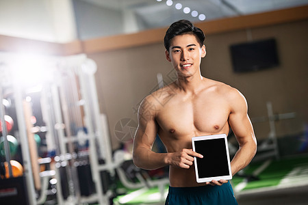 腹肌运动员健身青年男人展示平板电脑图片