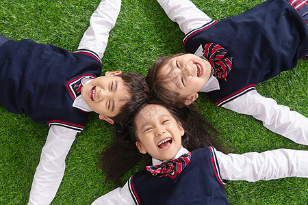 小孩嬉戏6岁到7岁生长希望小学生们躺在草地上背景
