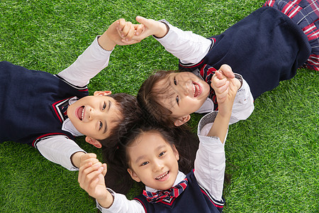 草地嬉戏未来高兴的女生小学生们躺在草地上背景