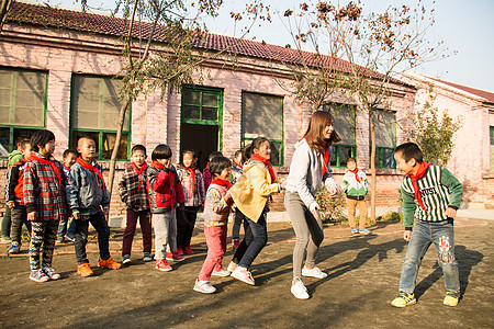 一群女生男生摄影乡村教师和小学生在学校里做游戏背景