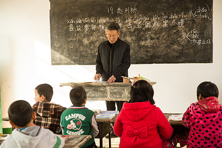 小学生卡通希望相伴逆境乡村男教师和小学生在教室里背景