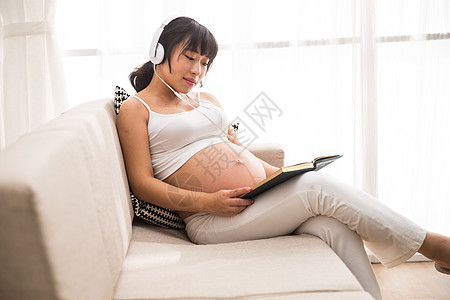 女性腹部满意幸福胎教孕妇听音乐看书背景