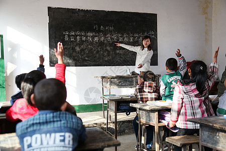 青年志愿者男生课桌希望乡村女教师和小学生在教室里背景