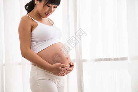 女性腹部20多岁关爱户内幸福的孕妇背景