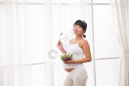 期待20到24岁东亚幸福的孕妇吃蔬菜沙拉图片