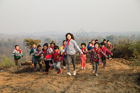 奔跑的男孩小学女生快乐志愿者乡村女教师和学生在玩耍背景