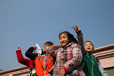 学校活动欢乐8岁到9岁男孩乡村小学生在学校放纸飞机背景