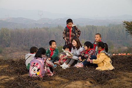 坐着山亚洲乡村教师和小学生在户外学习图片