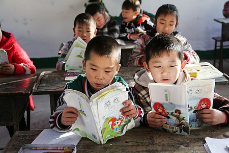 坐着读书的女孩关爱亚洲人坐着乡村小学里的小学生背景