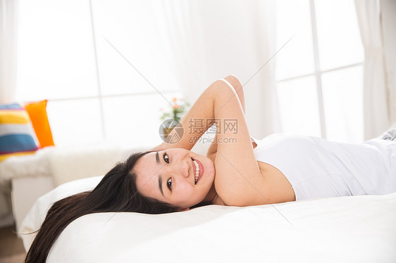 住房床上用品可爱的青年女人在卧室的床上图片