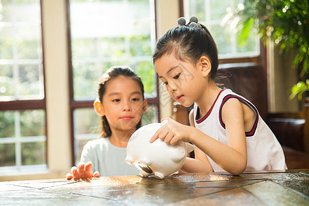 小孩存钱罐玩耍货币亚洲姐妹俩把钱放入存钱罐背景